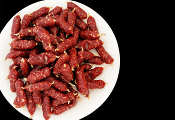 Mini sausages on a plate on a black background