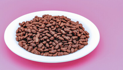 Bunch of chocolate rice on a pink background, side view