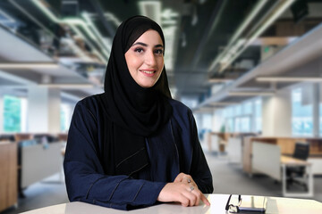 Happy smiling Emirati Arab woman wearing traditional Abaya and Hijab inside the office