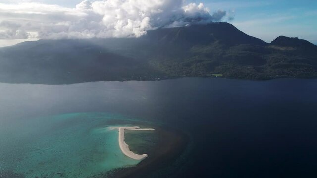 Tropical reef in sea with white sand bar on top, view of Camiguin island