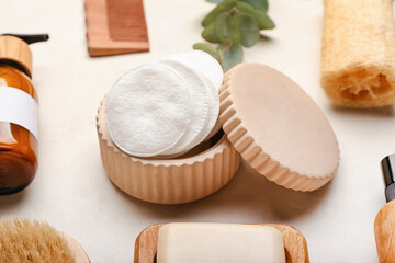 Cotton pads and cosmetic products on light background, closeup