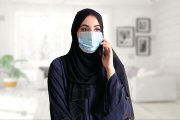 Middle East Arab woman wearing face mask, abaya and hijab while at home