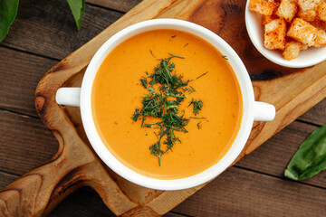 Lentil cream soup with dill and croutons on wooden background