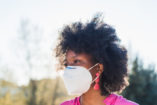 Smiling black woman in protective respirator in summer park