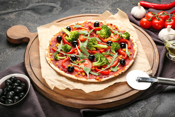 Board with tasty vegetarian pizza and knife on dark background