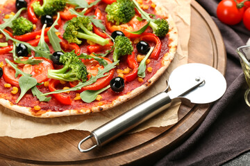 Board with tasty vegetarian pizza and knife on table, closeup