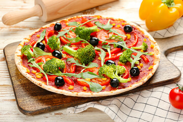 Board with tasty vegetarian pizza on light wooden background, closeup