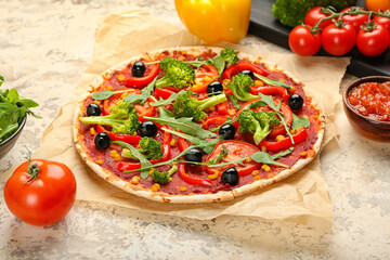 Parchment with tasty vegetarian pizza and sauce on light background