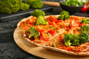 Board with tasty vegetarian pizza on dark background, closeup