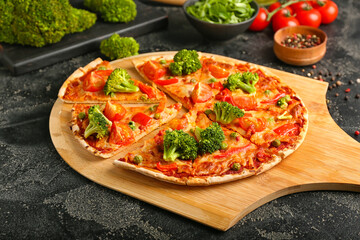 Board with tasty vegetarian pizza on dark background