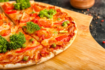 Board with tasty vegetarian pizza on dark background, closeup