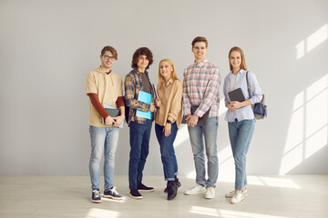University, college or high school education. Teenage diverse student classmates or friends, group of young smiling people with book and copy-book standing in row full body studio portrait