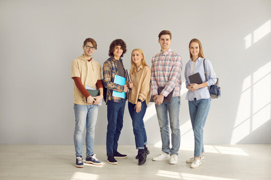 University, College Or High School Education. Teenage Diverse Student Classmates Or Friends, Group Of Young Smiling People With Book And Copy-book Standing In Row Full Body Studio Portrait