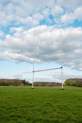 Fototapeta na wymiar Tall goal posts for Irish national sports, camogie, hurling, Gaelic football, soccer and rugby. Warm sunny day. Blue cloudy sky. Vertical image