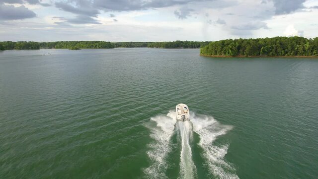 Aerial view of lake and boat running in the water. Green lake with green trees in the summer