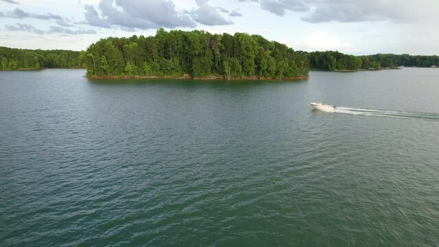 Aerial view of Lake with shiny water and green trees. Sun reflection in the water. Beautiful spring landscape with open water