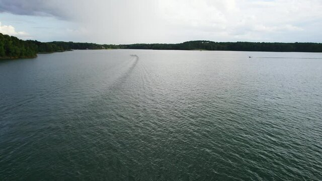 Aerial view of Lake with shiny water and green trees. Sun reflection in the water. Beautiful spring landscape with open water