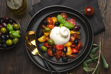 Italian fresh burrata cheese with tomatoes and olives. Caprese salad with mozzarella tomatoes and...