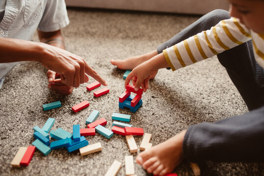 Anonymous father and son playing with construction pieces in the dining room