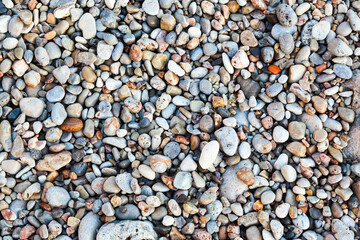 Stones of different shapes, sizes and colors on the seashore, close-up. Background of sea stones.