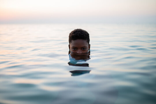 Black woman with short hair and half face in sea