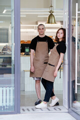 Bakers in aprons posing in the entrance in the transparent shop front