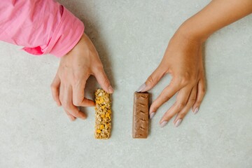 Obraz premium Person holding a chocolate bar and granola bar