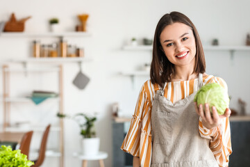 Young woman with fresh cabbage in kitchen