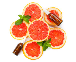 Bottles of essential oil and slices of grapefruit on white background