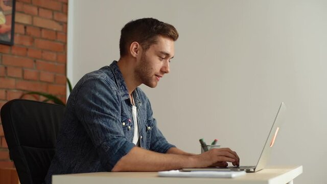 Happy freelancer relieved to have met deadline, finish work on laptop sitting at desk at home office. Close-up of successful young businessman finishing work, closing computer. Shooting in slow motion