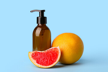 Bottle of essential oil and grapefruits on color background
