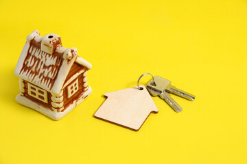 House and keys with keychain on yellow background, sale and purchase of an apartment.