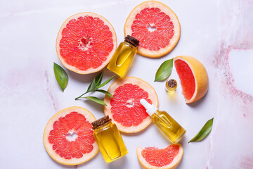 Composition with bottles of essential oil and grapefruit slices on light background