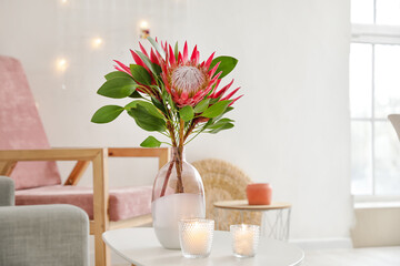 Table with protea flowers and candles in interior of room