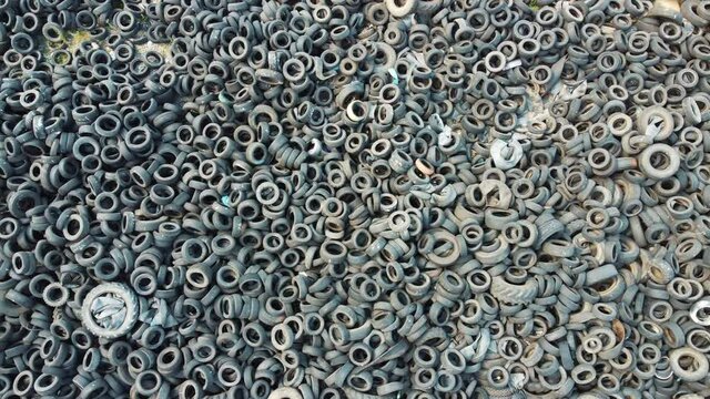 Lots of discarded tires at tire dump. Pile of old tires and wheels for rubber recycling. Industrial factory for the processing of waste tires. Environmental pollution, Ecology, Recycling.