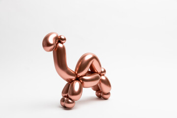 A cute little camel made from a 260 magic balloon with a Reflex Rose gold color on a white background.