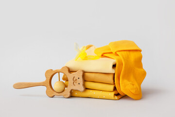 Stack of baby clothes, pacifier and rattle on grey background