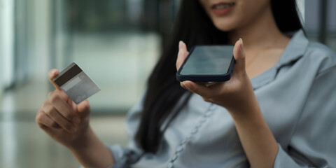 Hands holding smartphone blank screen and credit card.
