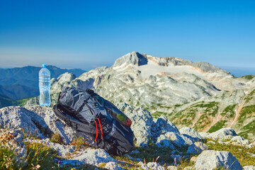 A bottle of clean water on the top of the mountain and a backpack, drinking on a hike
