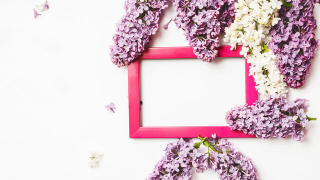 Pink photo frame and lilac flowers on a white background. Layout, flat lay, copy space, top view.