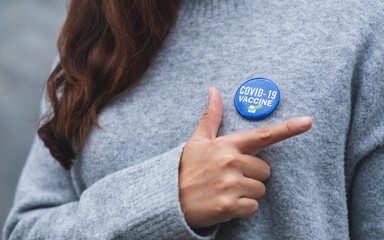 Closeup image of a young woman showing Covid-19 vaccinated sign brooch on shirt