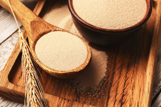 Bowl and spoon with active dry yeast on table, closeup