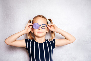Happy little girl wearing glasses and eye patch or occluder, amblyopia (lazy eye) treatment