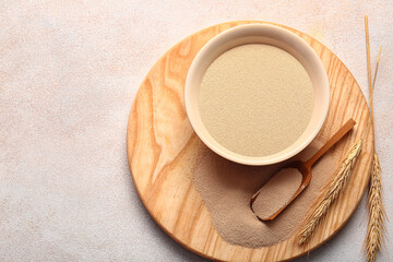 Bowl and scoop with active dry yeast on light background