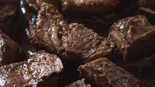 Close up of chunks of steak being cooked in a pan.