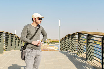 Young man taking a walk in a park with lakes on a sunny autumn day.