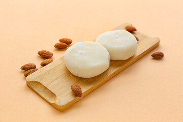 Board with tasty Japanese mochi and nuts on color background