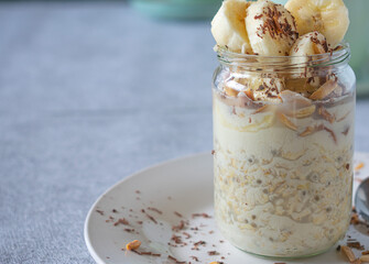 Oatmeal with bananas, chocolate, roasted almonds and chia seeds in a glass jar