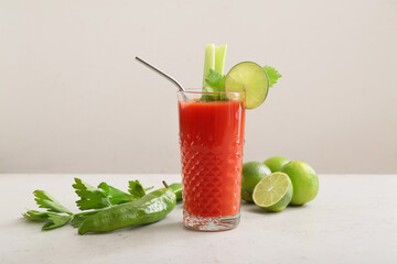 Glass of bloody mary cocktail and ingredients on light background