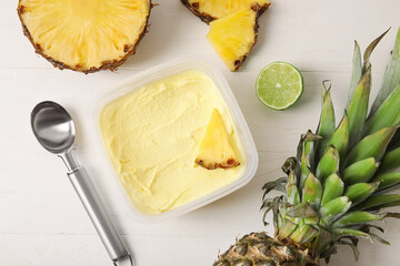 Container with tasty pineapple ice cream on light wooden background